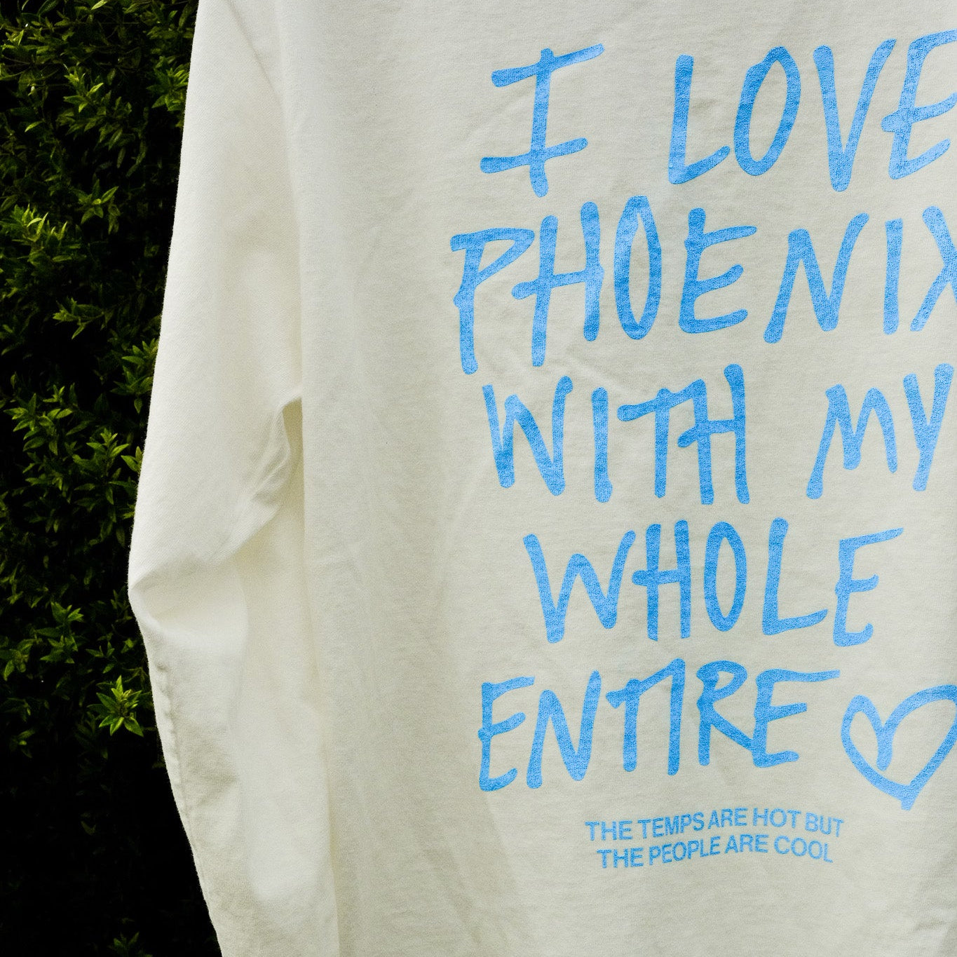 White sweatshirt with blue text 'I love Phoenix with my whole entire' on a dark background